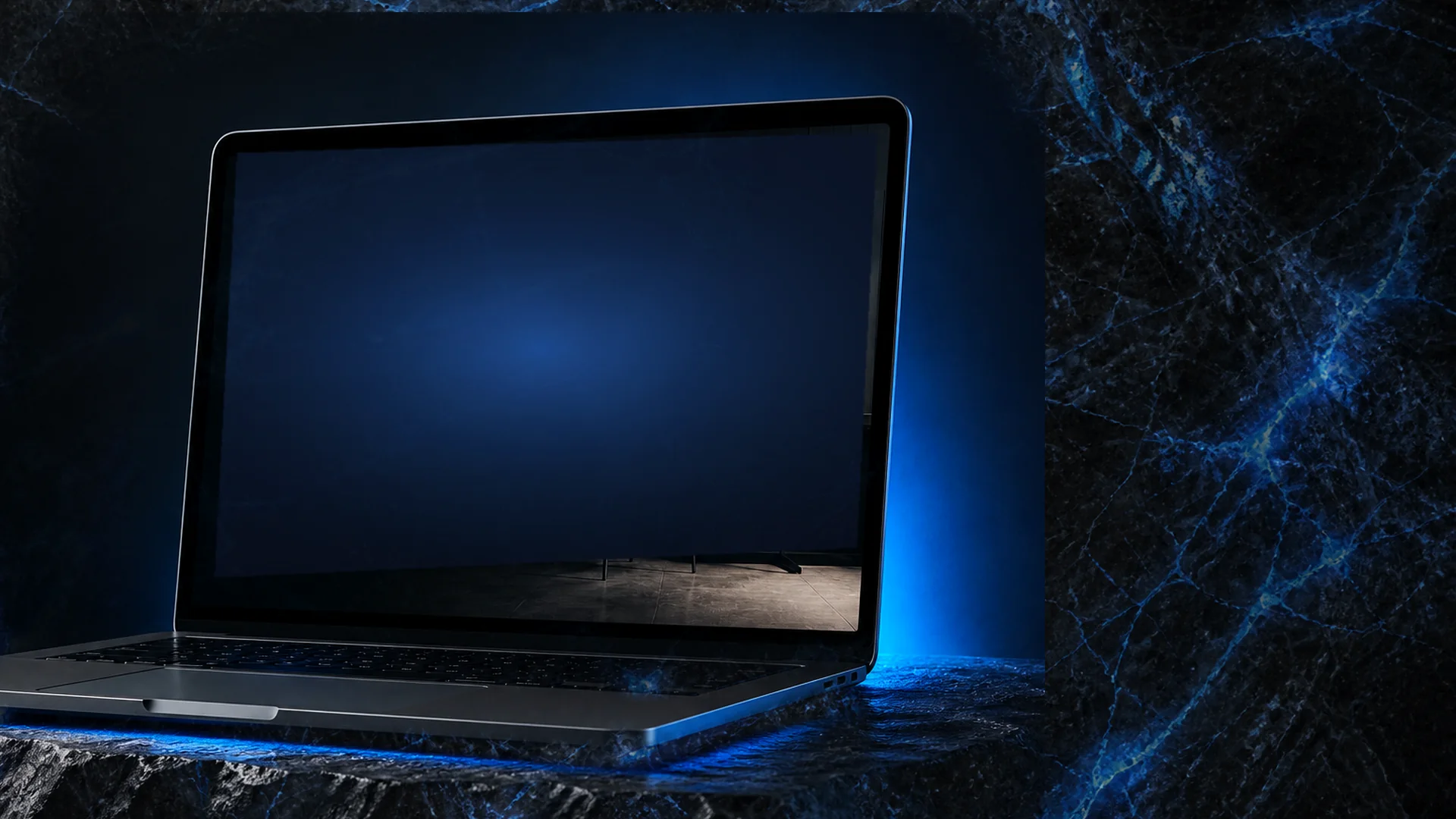 אותו מחשב מהעבודות, על שיש כהה עם ורידים כחולים. המסך כבוי — מחכה לשם שלכם.